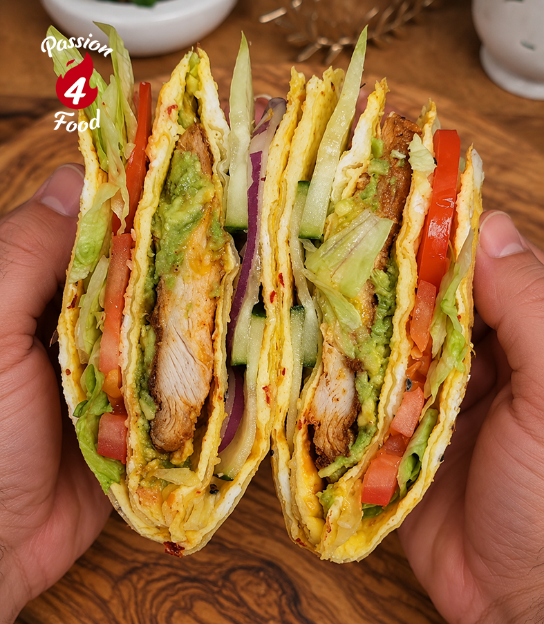 Hands holding a cut vegetable and chicken wrap with lettuce, tomato, and crispy filling