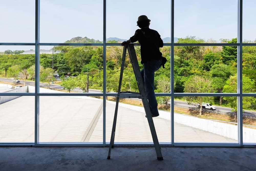 Person On A Ladder Looking Out A Window - Glass Repair in Gold Coast, QLD