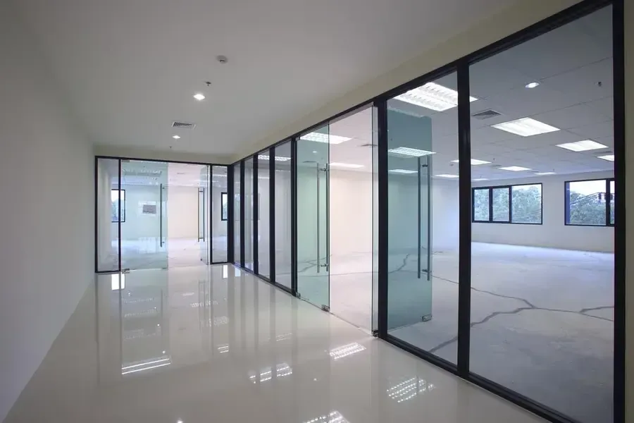 Modern office hallway with glass-walled rooms and glossy white floors