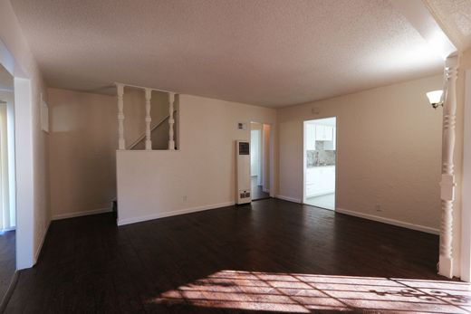 West Covina Empty living room with beige walls, dark wood floors, and sunlight streaming through a window.
