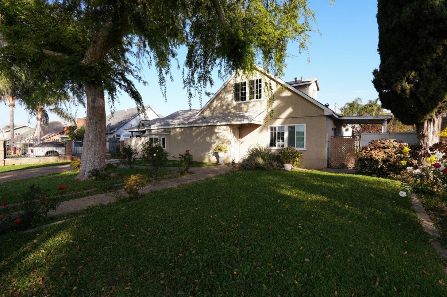West Covina Suburban house with a green lawn, large trees, and a sunny front yard