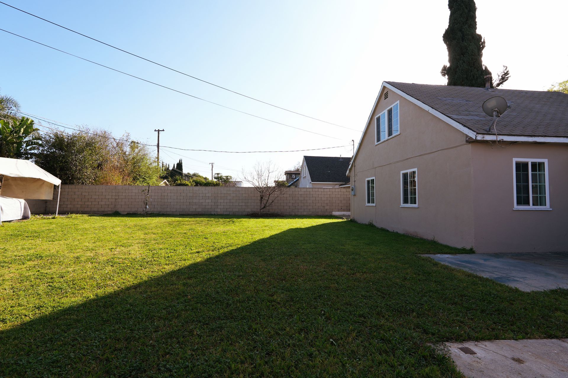 West Covina Backyard with green lawn beside a beige house under a clear sky