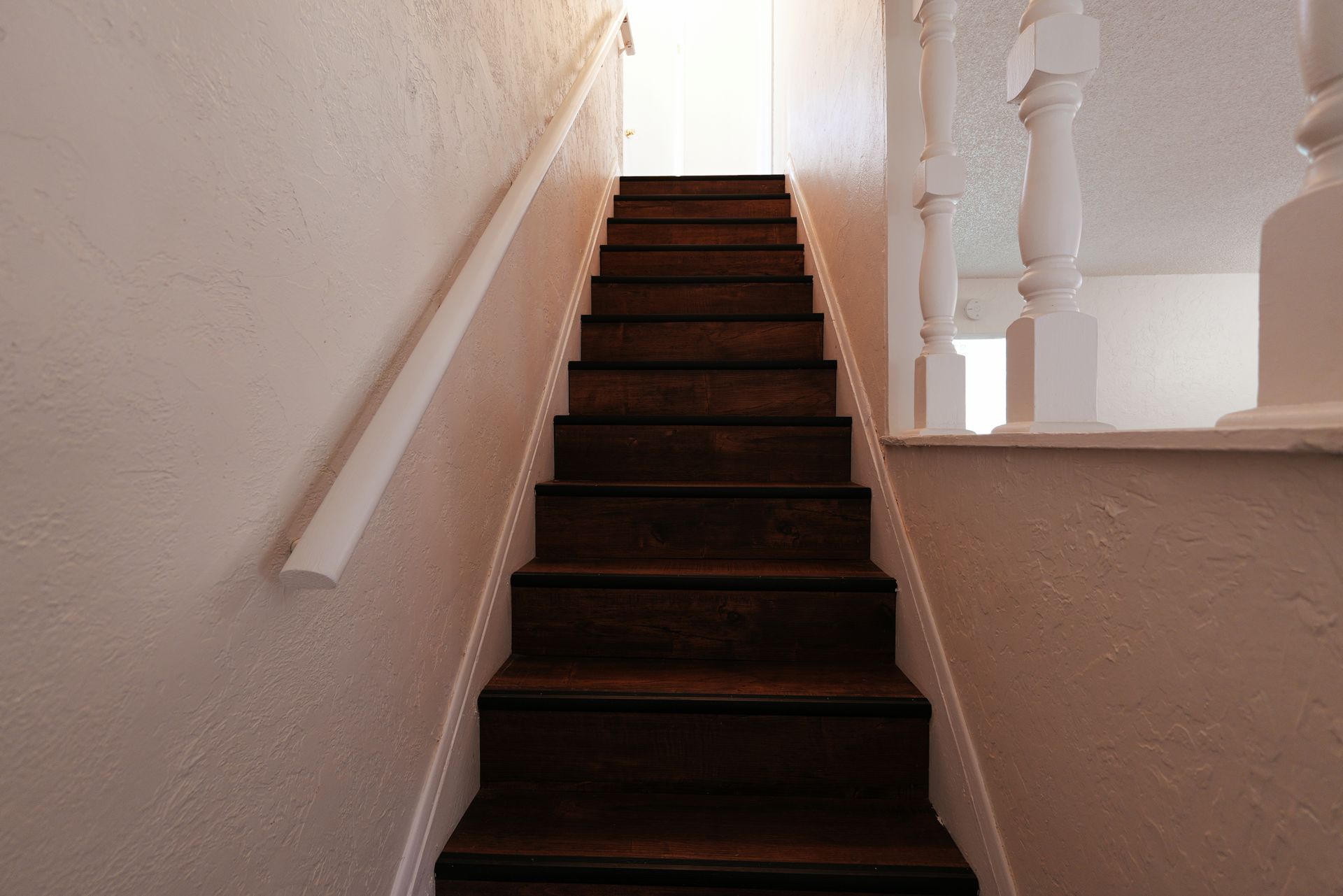 West Covina Narrow carpeted staircase with white walls and railing leading to a bright landing