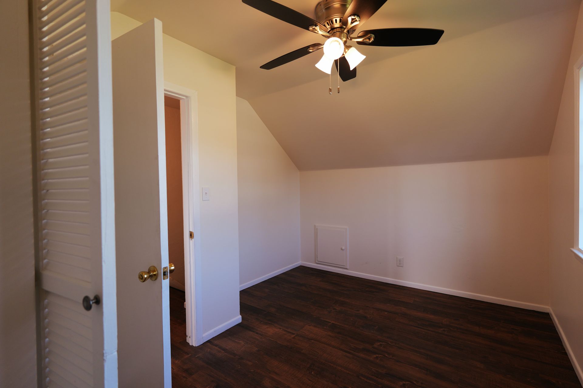 West Covina Empty bedroom with dark wood floor, white walls, slanted ceiling, and ceiling fan.