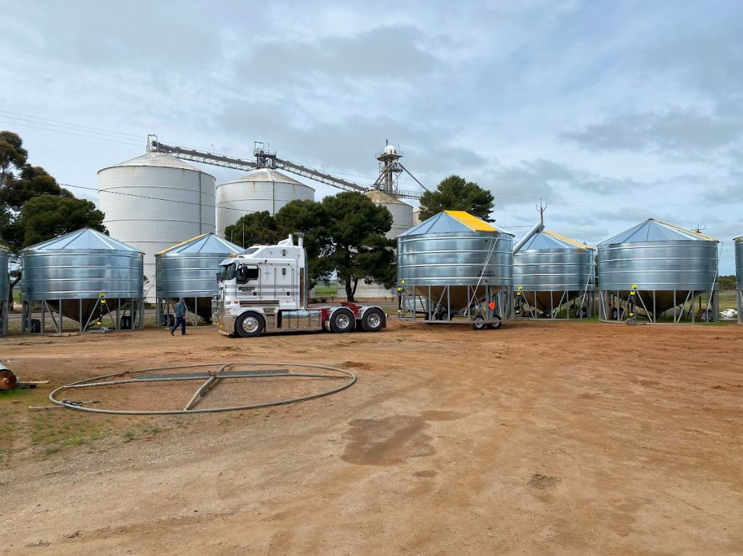 A truck is parked in front of a row of silos.