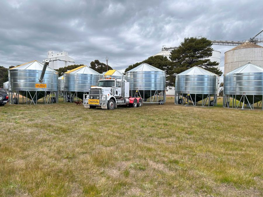 A truck is parked in a field next to a row of silos.