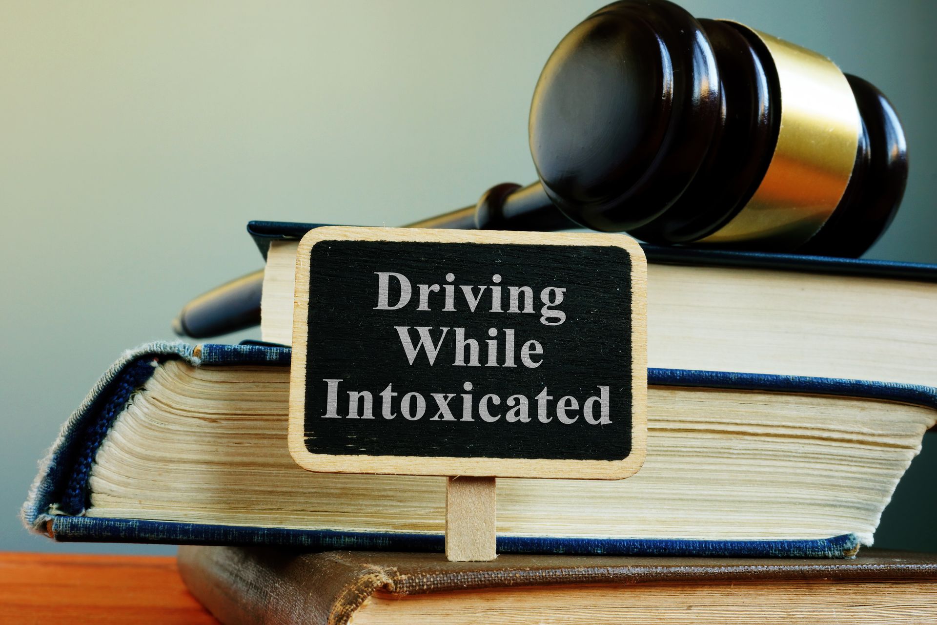 Gavel resting on law books beside a sign reading “Driving While Intoxicated.” Gavel resting on law books beside a sign reading “Driving While Intoxicated.”