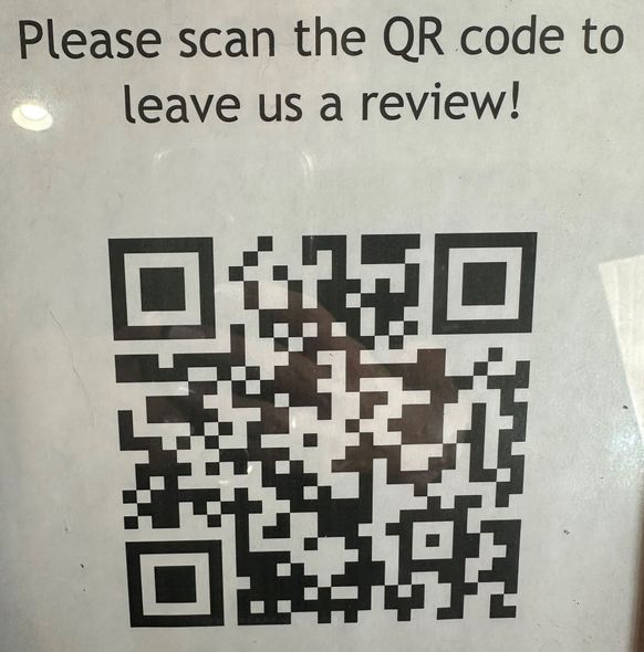 A sign that says please scan the qr code to leave us a review