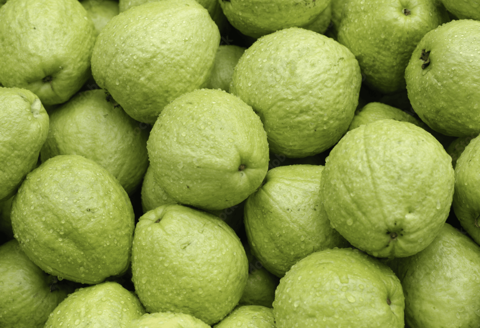 Un montón de manzanas verdes con gotas de agua sobre ellas.