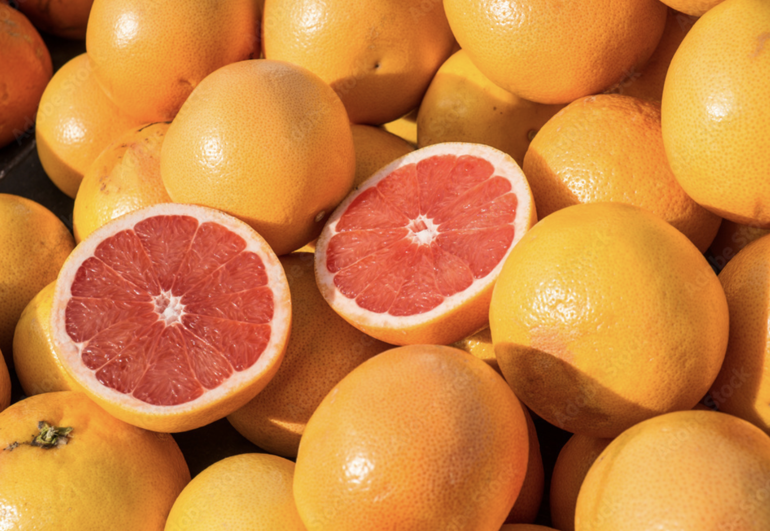 Un montón de pomelos con uno cortado por la mitad