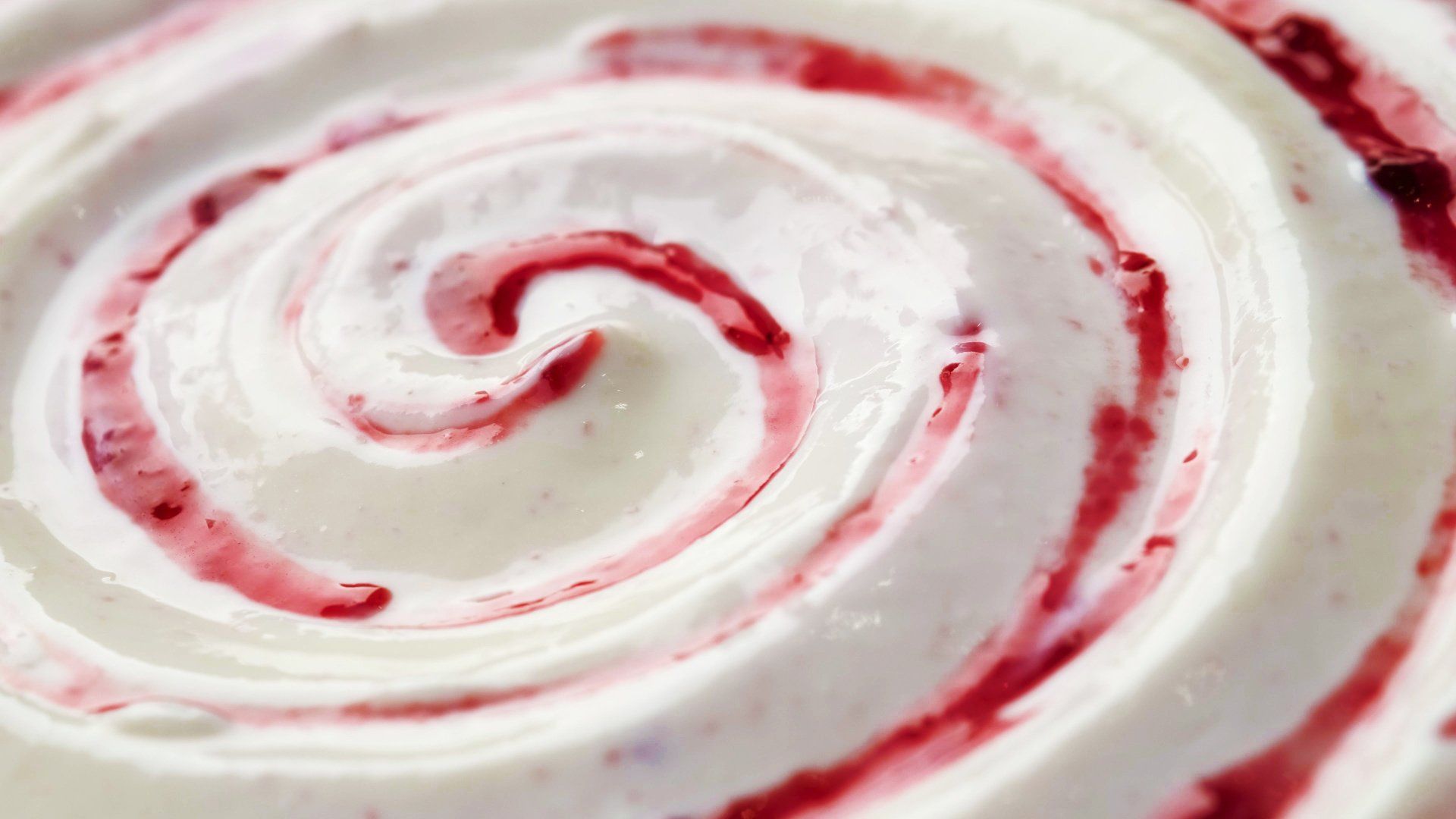 Un primer plano de un remolino de crema batida y salsa de bayas.