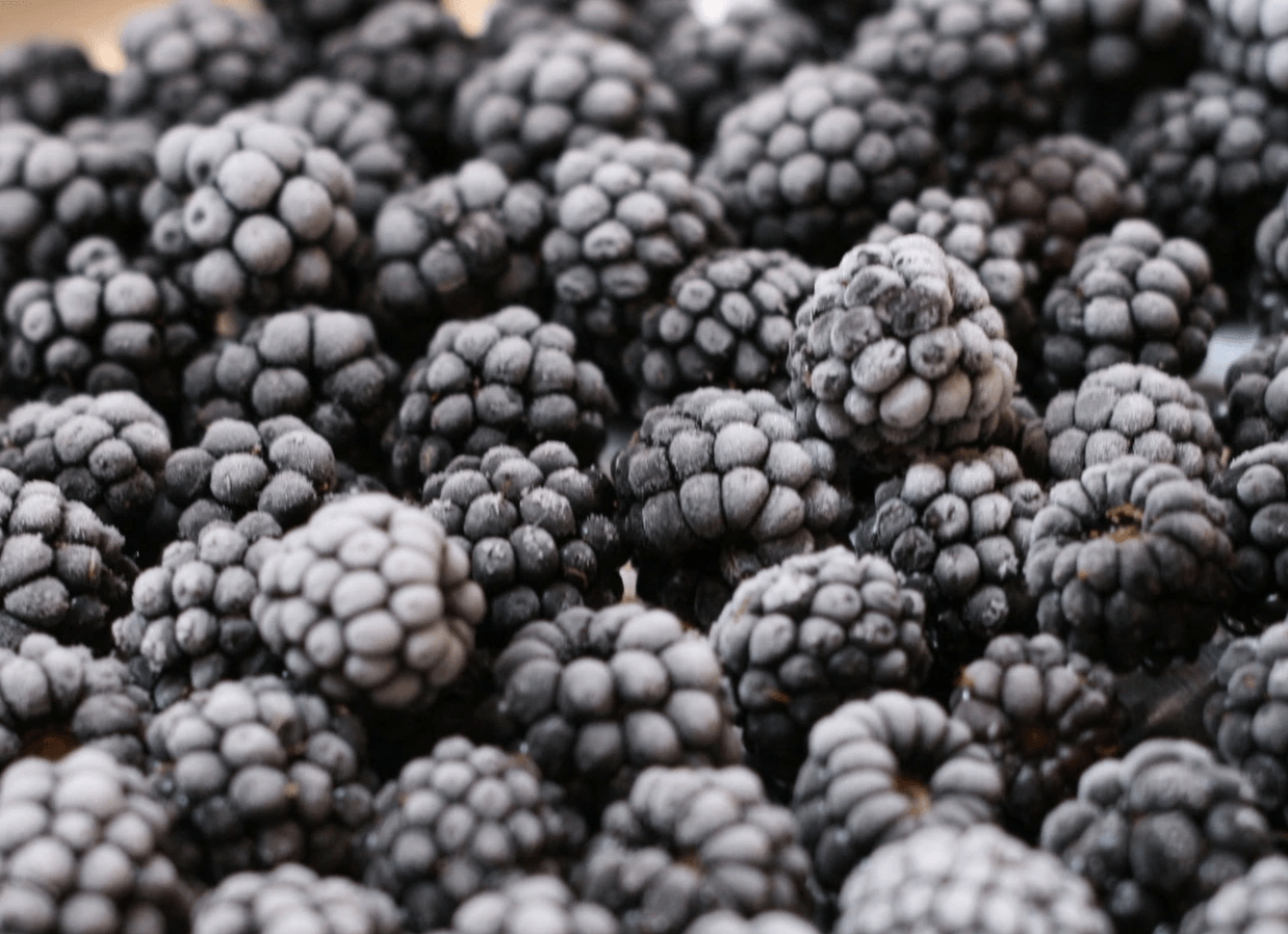 Un primer plano de una pila de moras congeladas sobre una mesa.