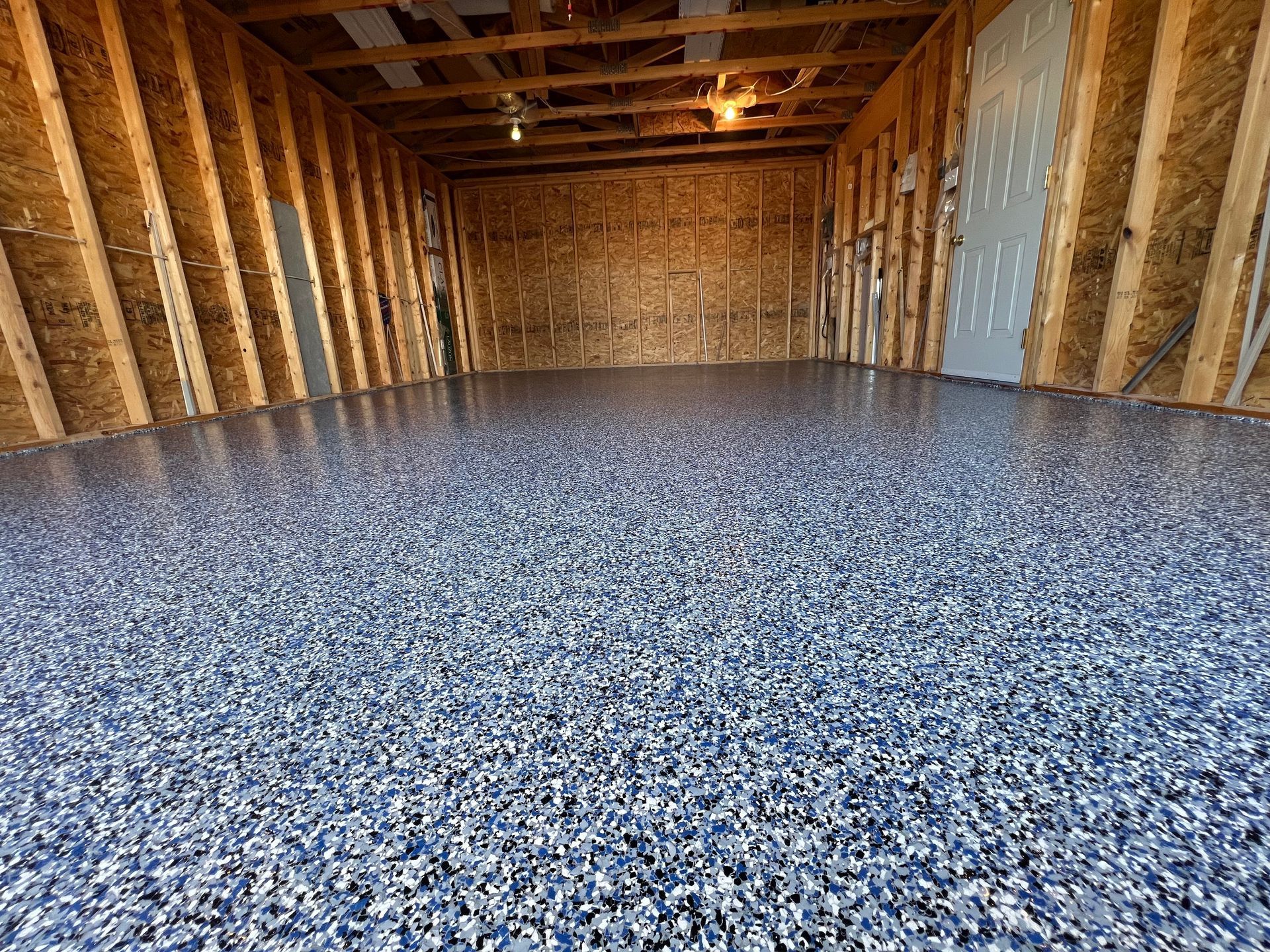 A garage with a blue epoxy floor and wooden walls.