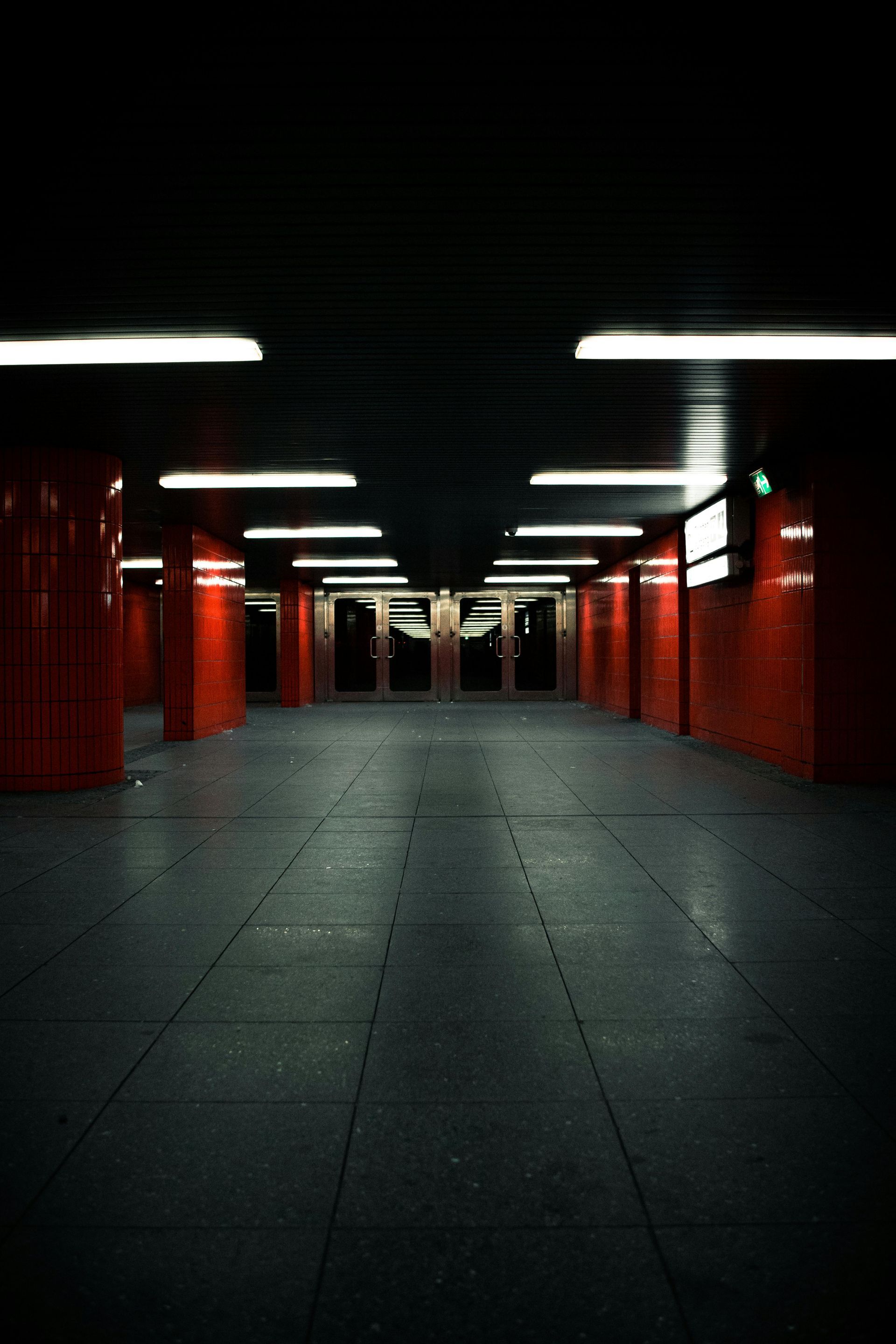 A dark hallway with red columns and lights on the ceiling