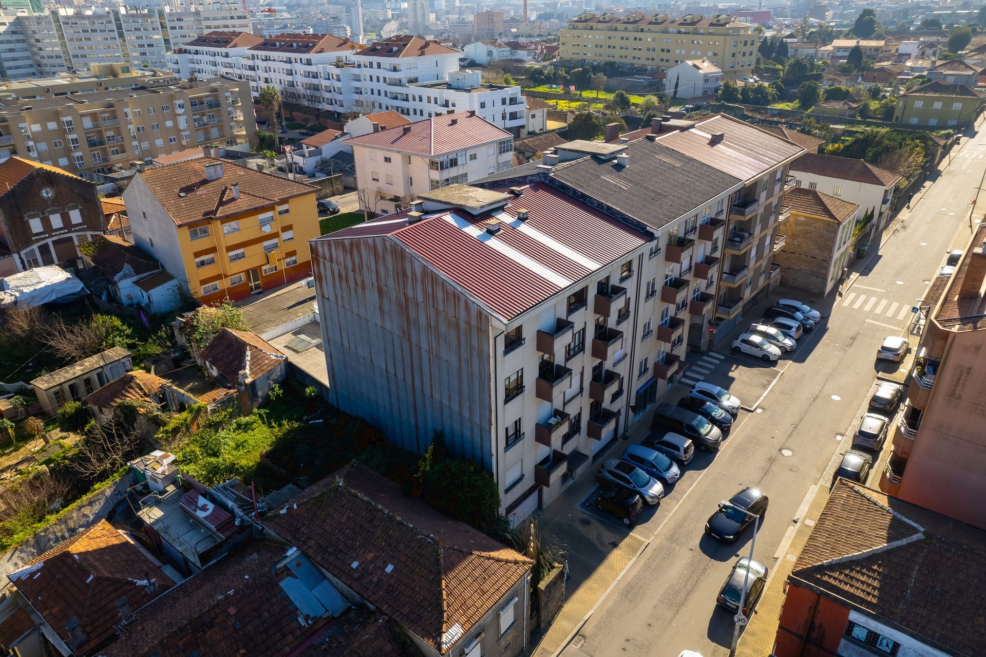 Vista aérea de edifícios de vários andares e carros estacionados ao longo de uma rua.
