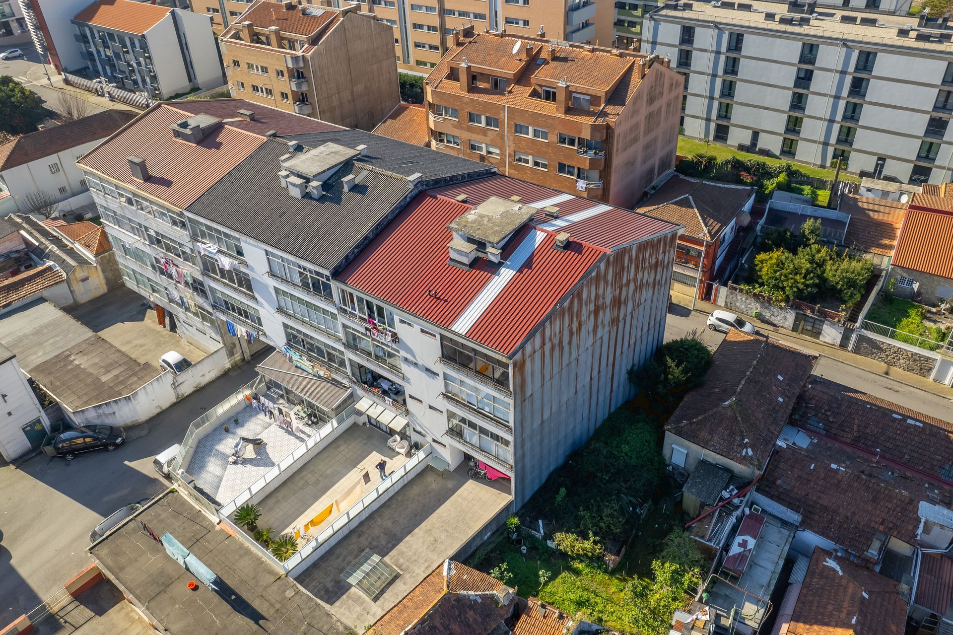 Vista aérea de edifícios de vários andares com telhados de telha vermelha e preta.