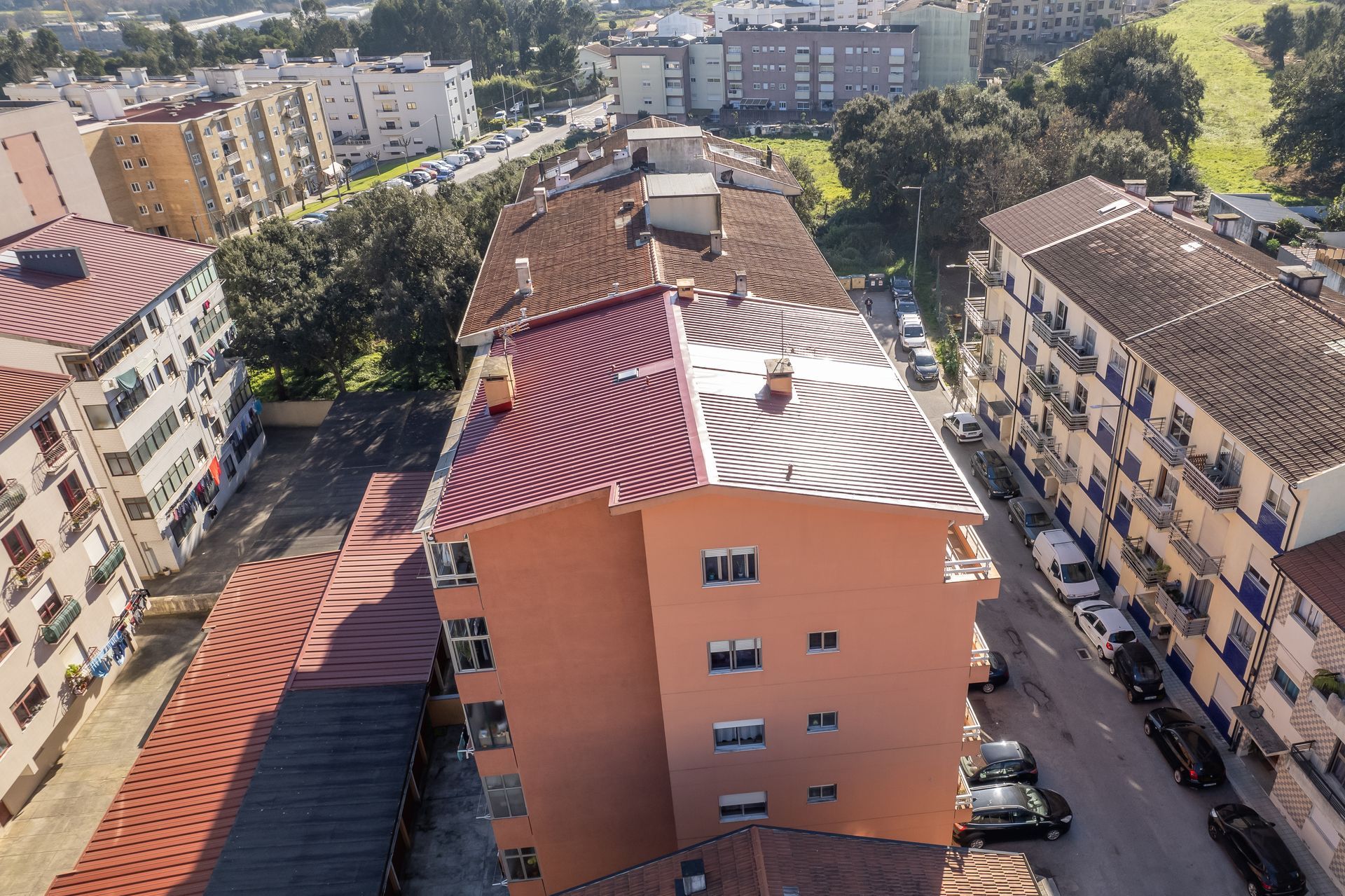 Vista de cima de prédios de apartamentos com telhados de telha vermelha e fachadas bege.