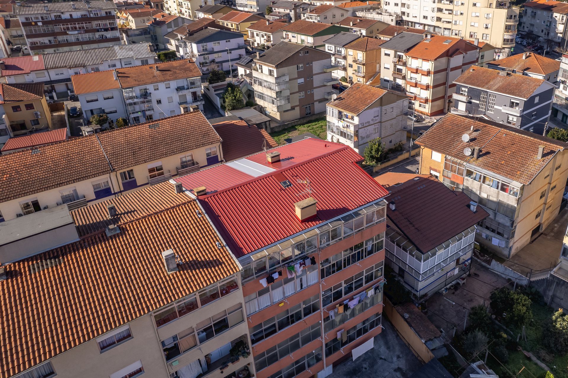 Vista aérea de edifícios densamente agrupados com telhados de telha laranja e vermelha.