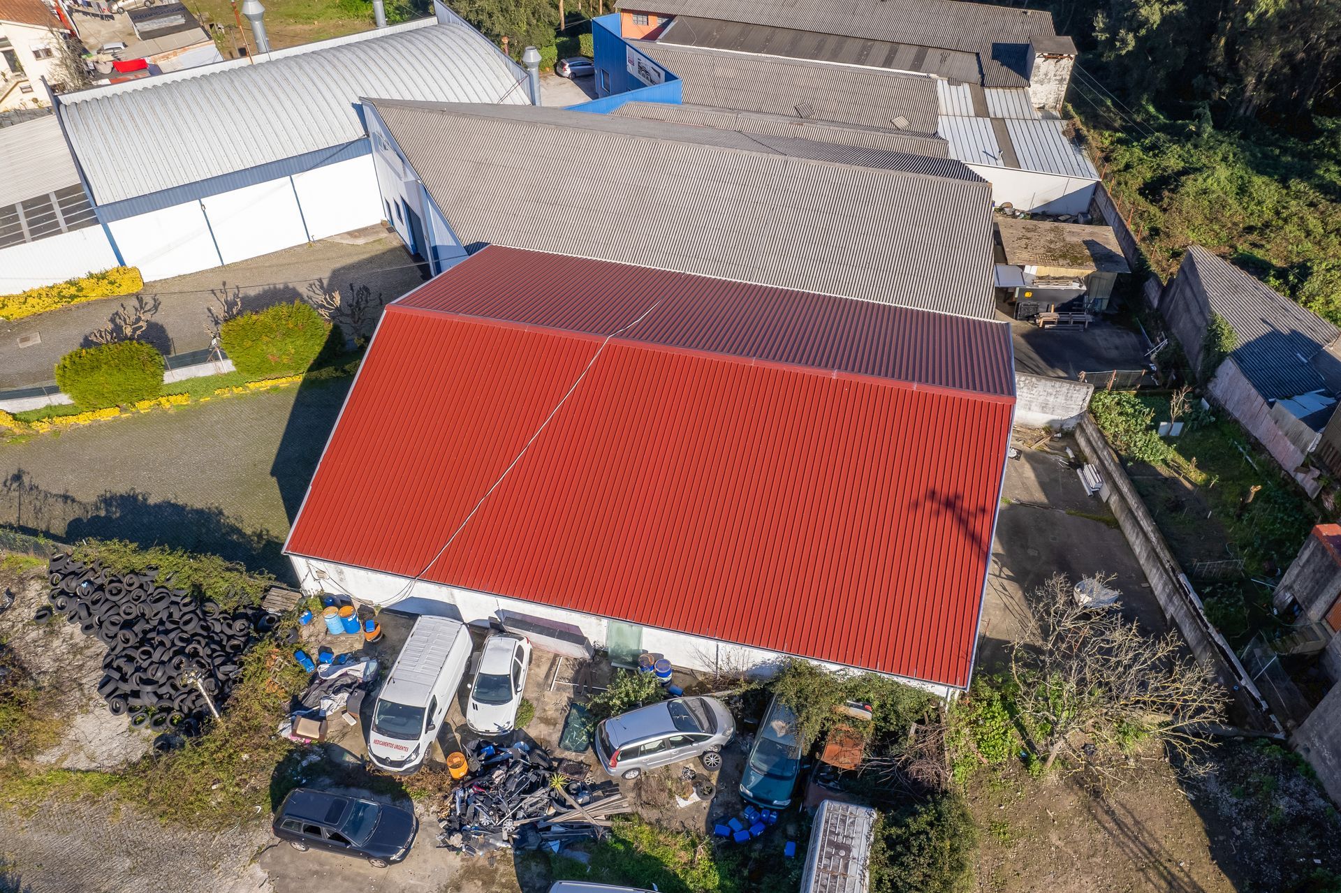 Vista aérea de um edifício com telhado vermelho e vários veículos estacionados em um ambiente externo.