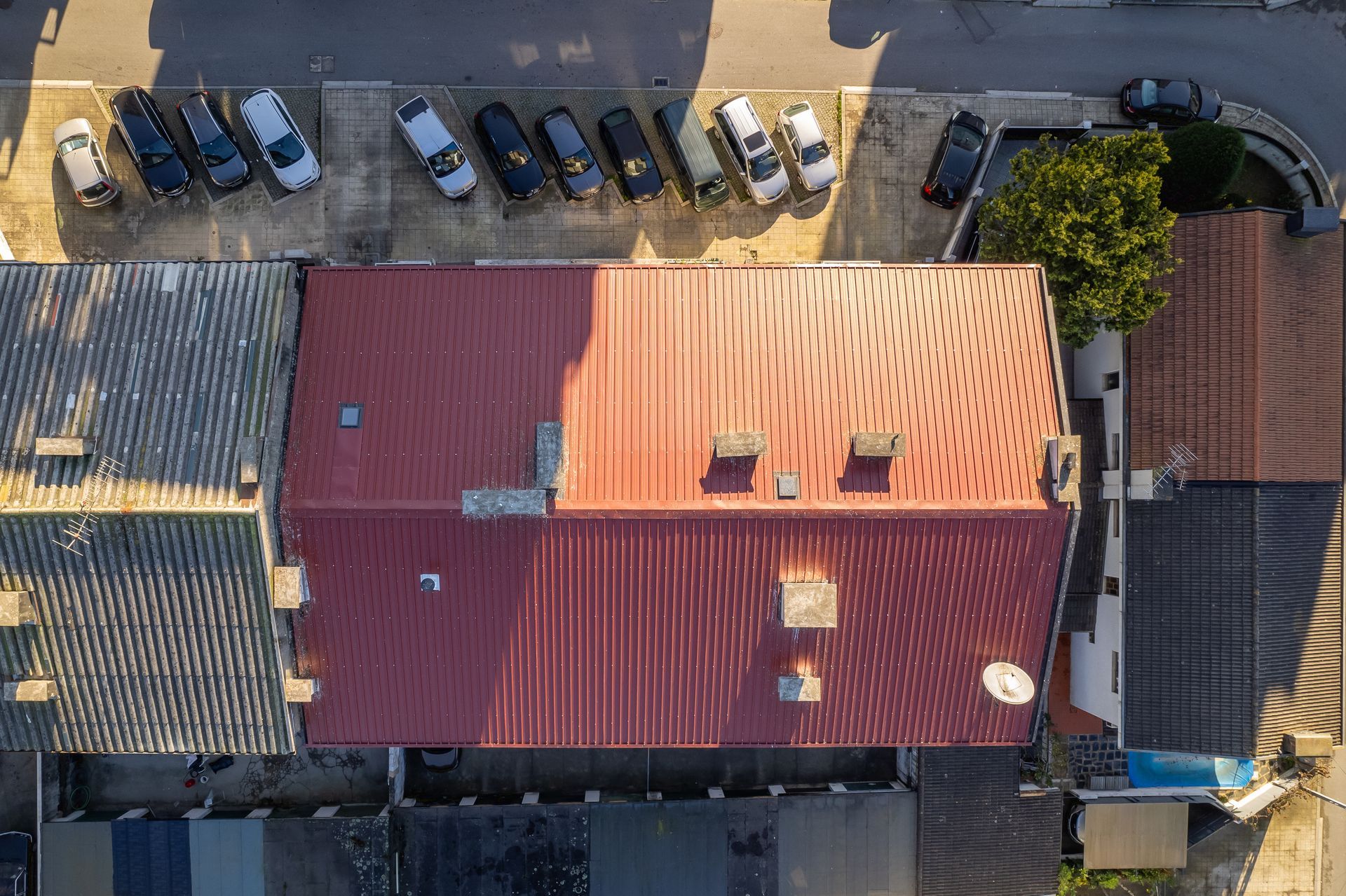 Vista aérea de vários edifícios com telhados vermelhos e cinzentos e um estacionamento com carros.
