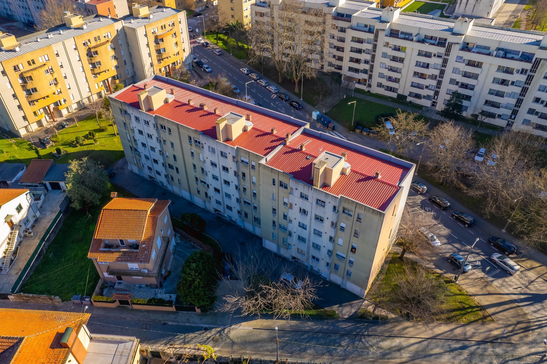 Vista aérea de edifícios residenciais com telhados vermelhos. Os edifícios são bege, com janelas e rodeados por vegetação.