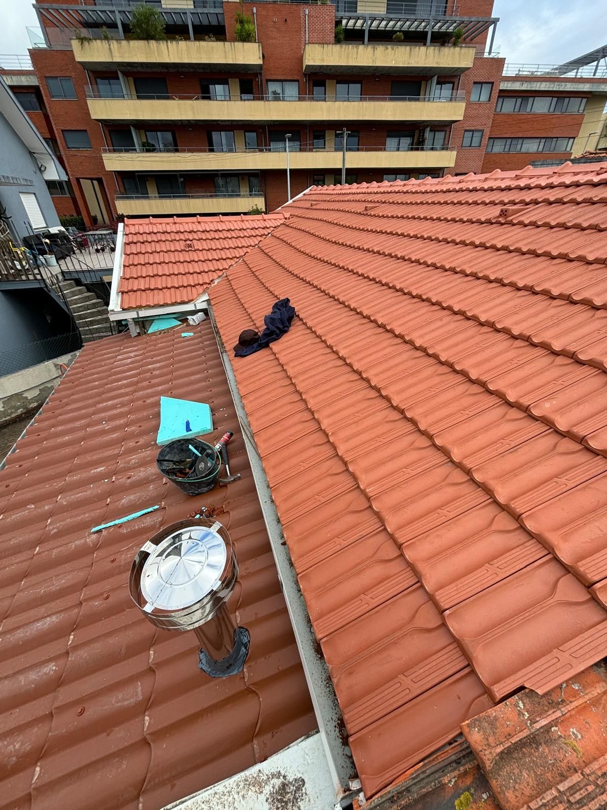 Um telhado de telhas cerâmicas laranjas com um edifício ao fundo.