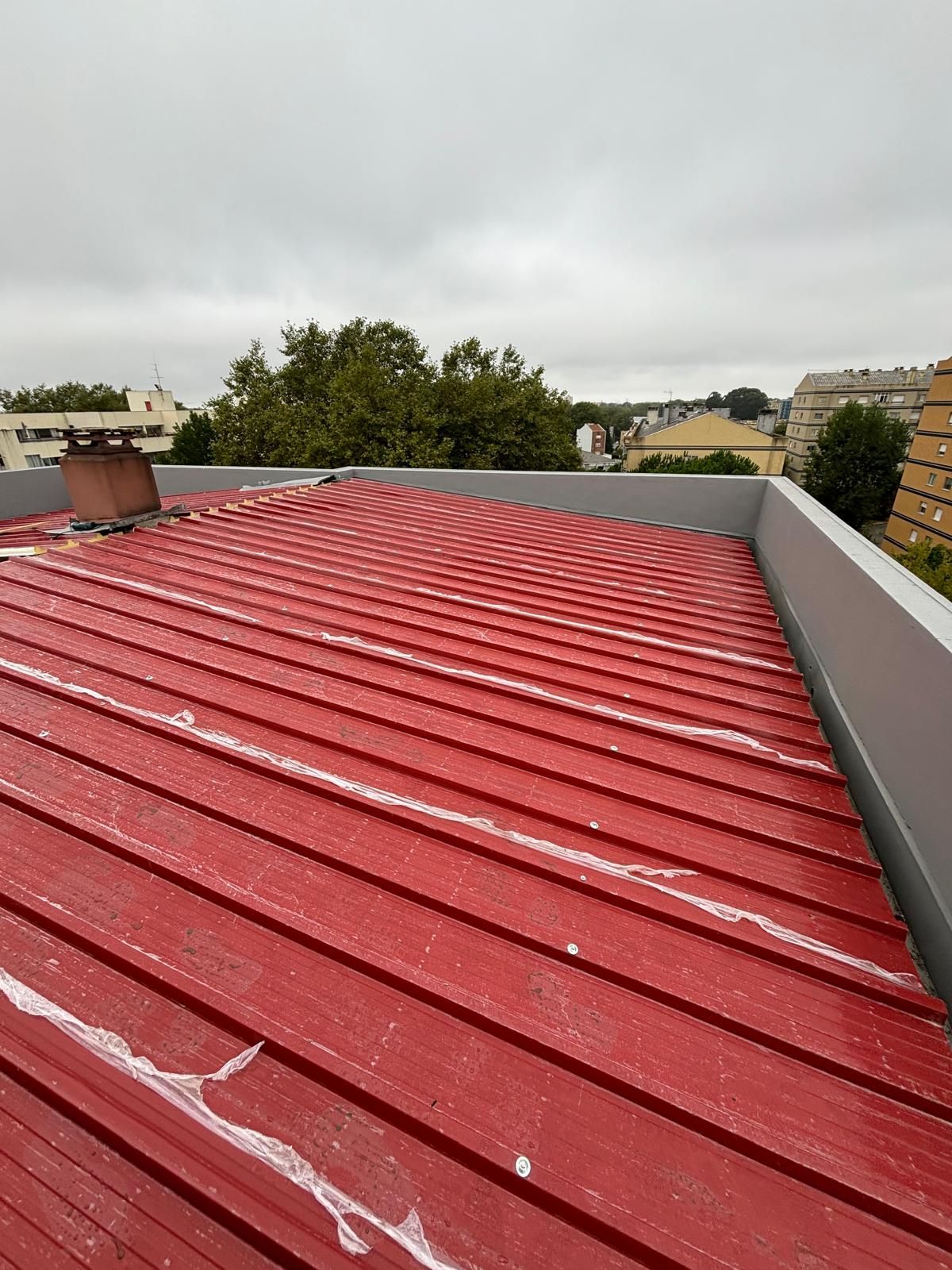 Um telhado em painel sandwich 5 ondas 30mm RAL3009 vermelho vermelho com uma chaminé em cima.