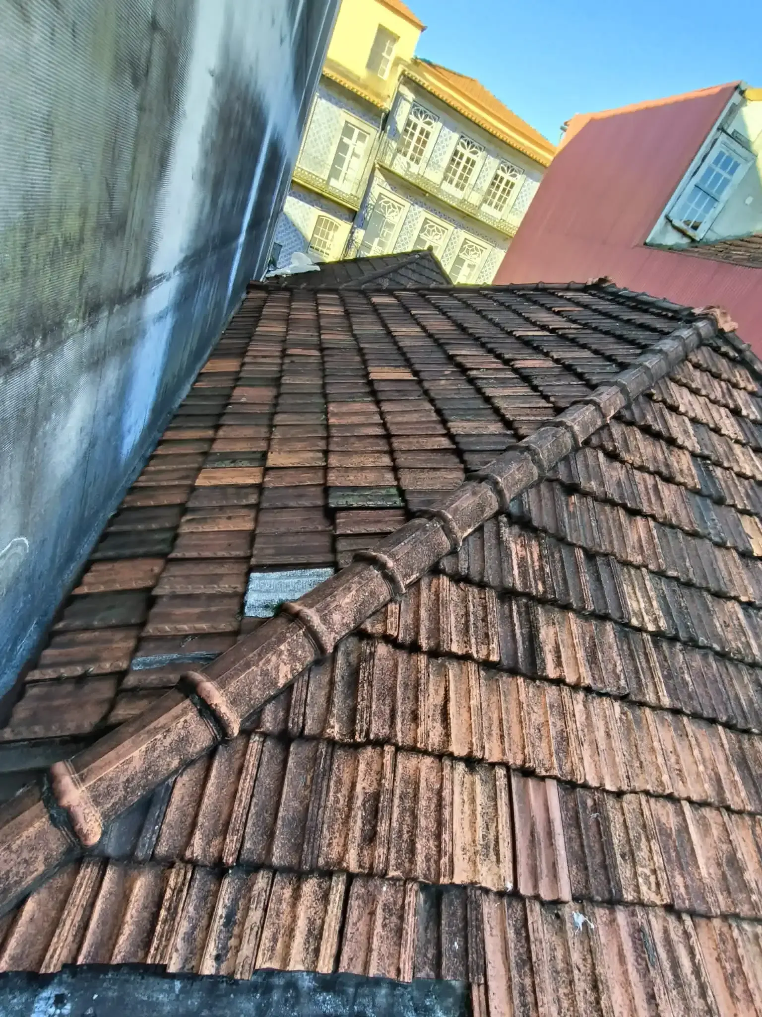 Um telhado com muitas telhas e um prédio ao fundo.
