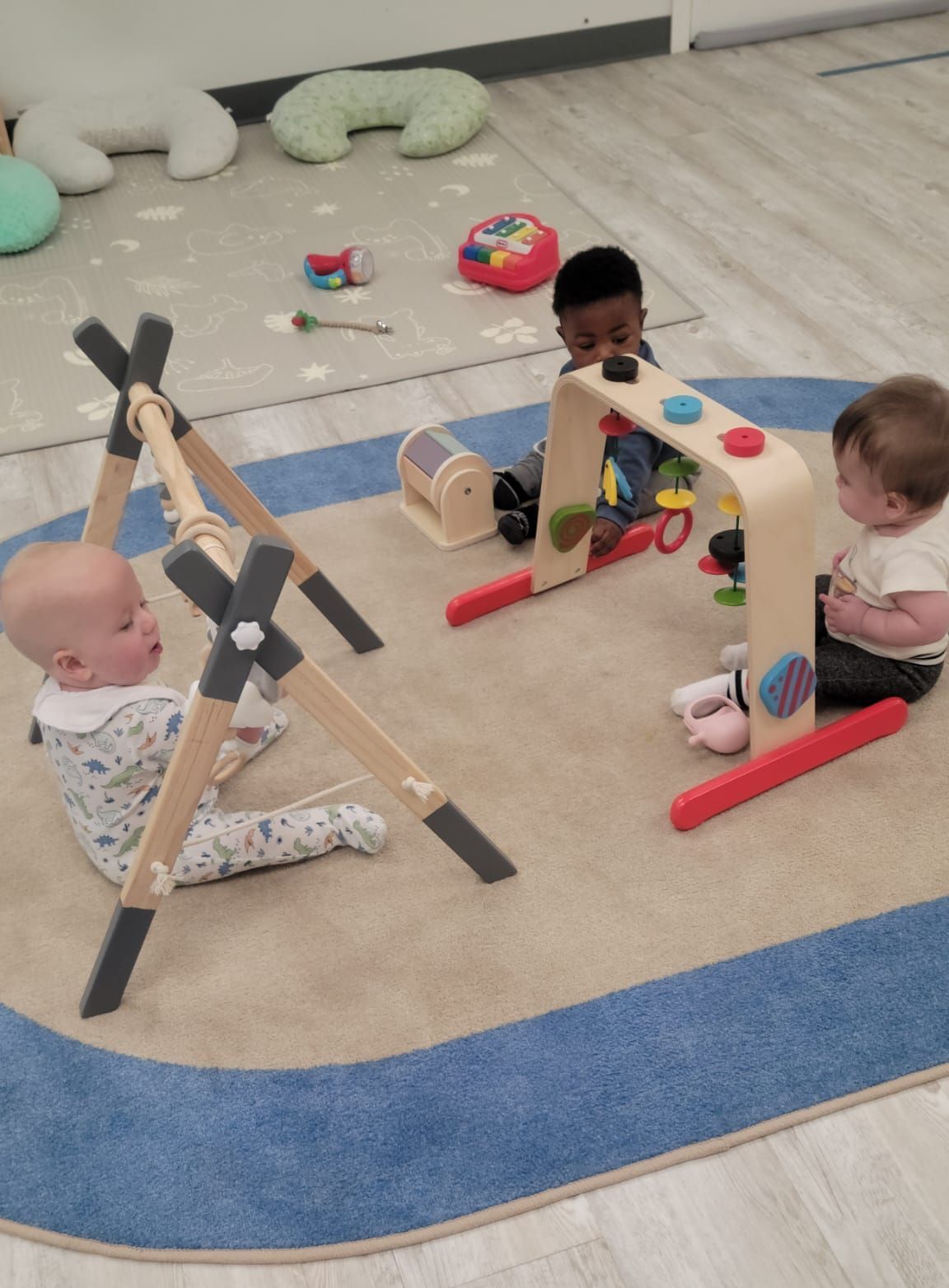 Two babies are playing with toys on a rug in a room.