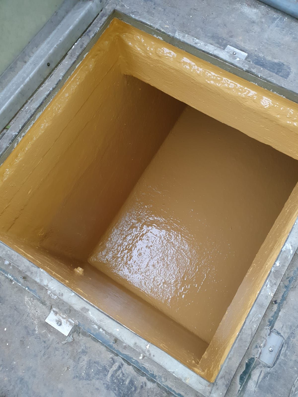 Scatola di cemento aperta e rettangolare, con interno marrone chiaro e uno strato di sostanza umida sul fondo.
