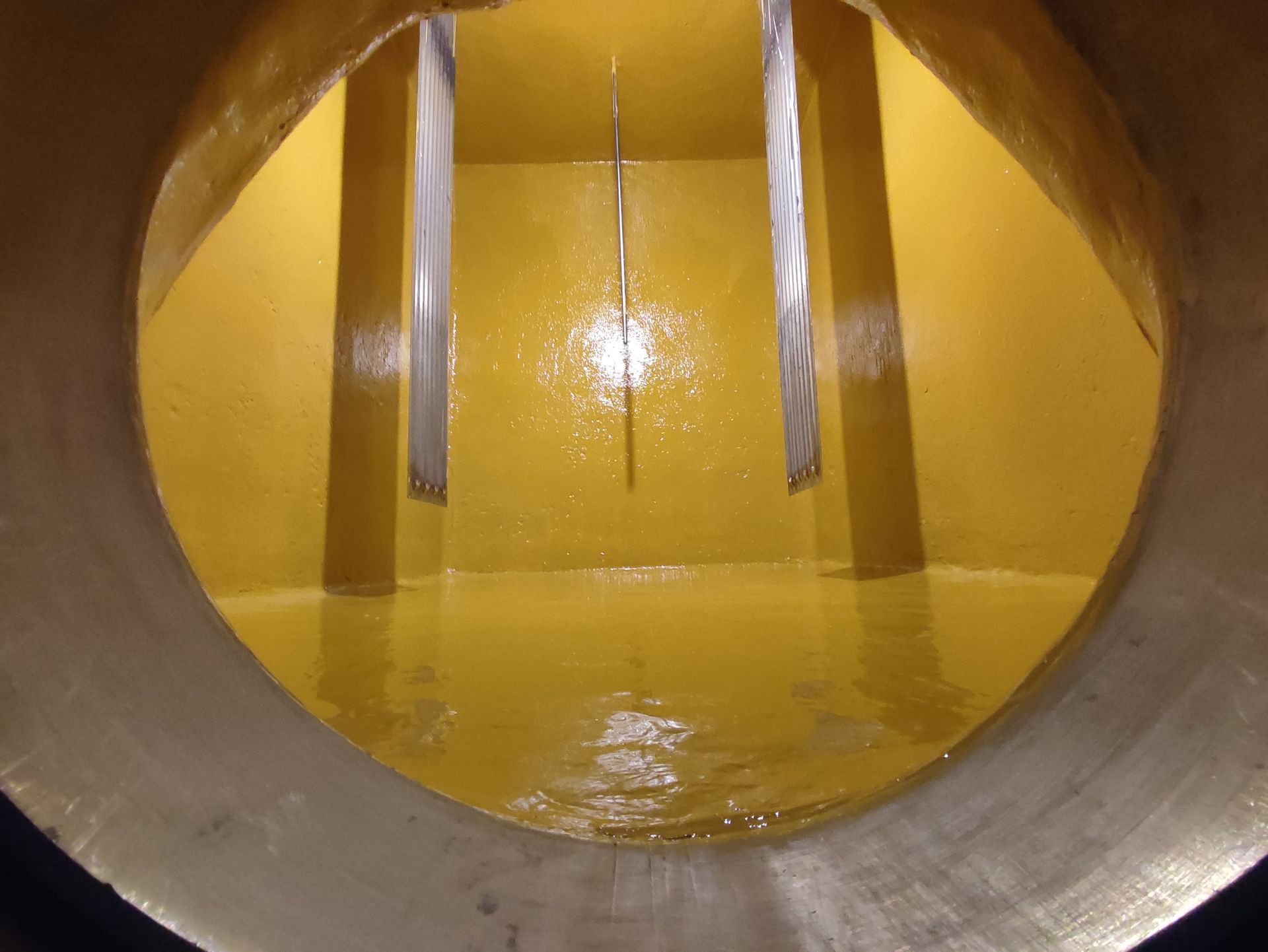 Vista interna di un serbatoio cilindrico giallo. All'interno sono sospese verticalmente diverse piastre metalliche rettangolari.