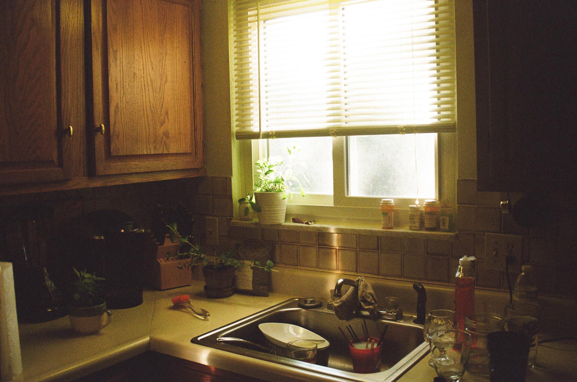 A kitchen with a sink and a window with blinds