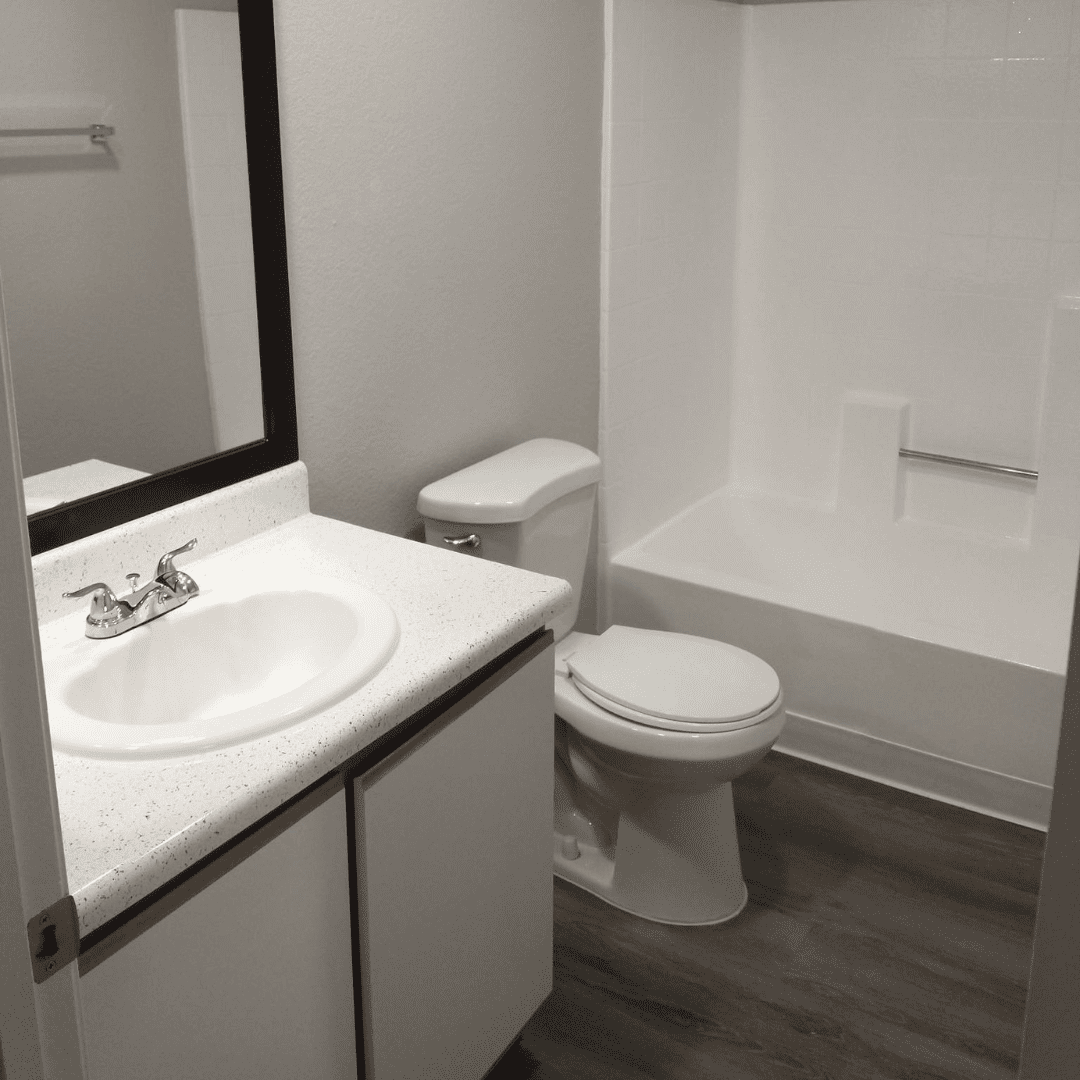Bathroom with white sink, toilet, and shower/tub combo. Gray floor.