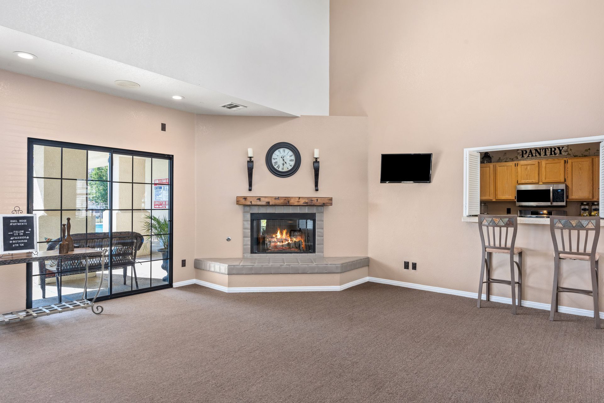 Cozy interior with fireplace, bar seating, glass doors, and a mounted TV on a beige wall.