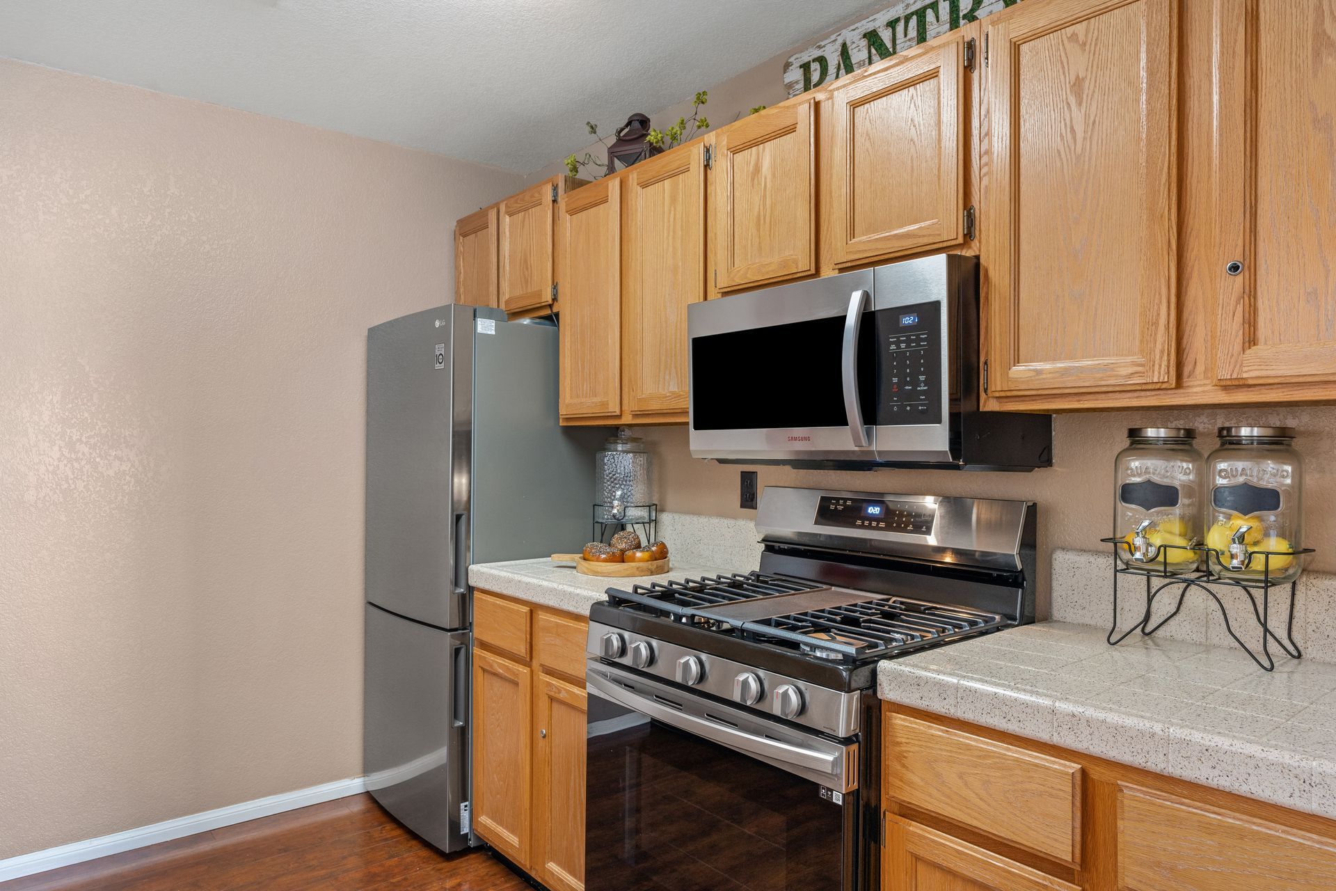 Kitchen with stainless steel appliances, light wood cabinets, and a beige countertop.