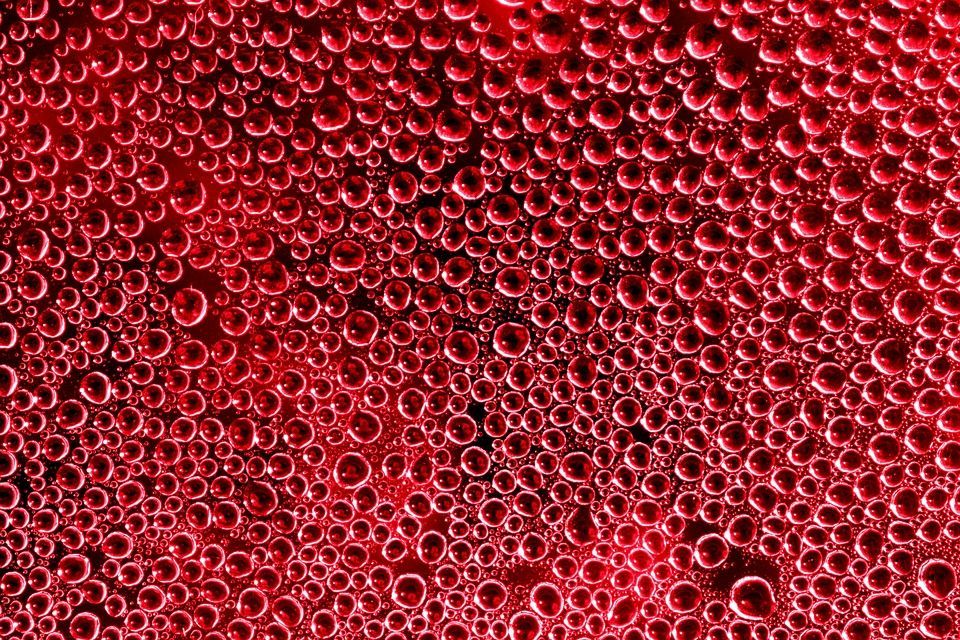 Close-up of dozens of red beads or bubbles densely packed together in a textured pattern