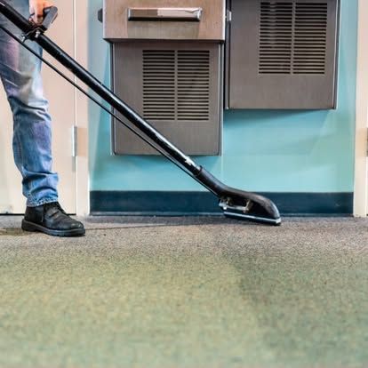 A person is using a vacuum cleaner to clean a carpet.