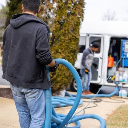 A man is holding a blue hose in front of a van.