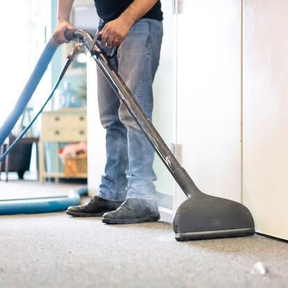 A man is using a vacuum cleaner to clean a carpet.