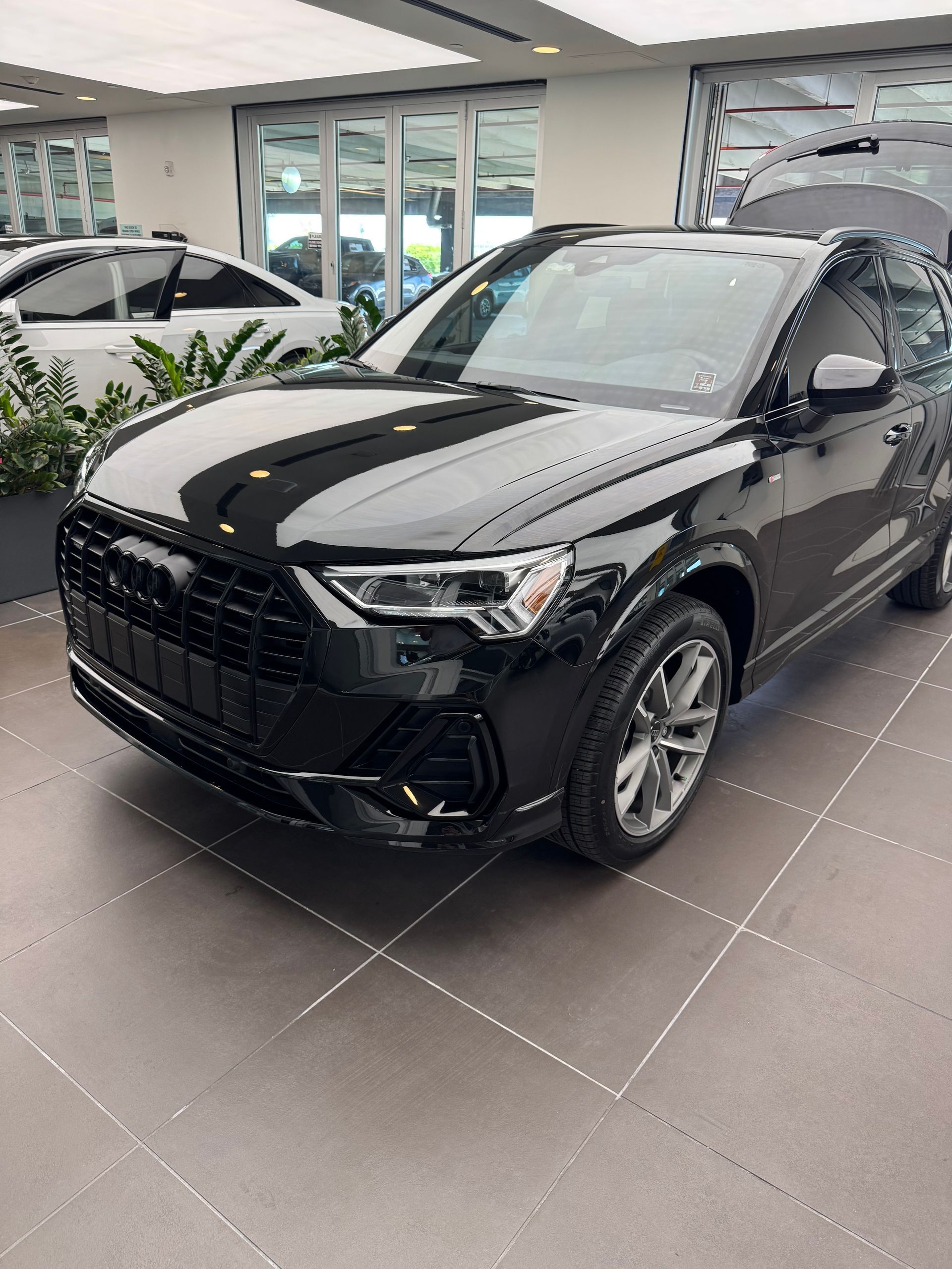 Black Audi Q3 SUV parked indoors, in a showroom with tile floor.