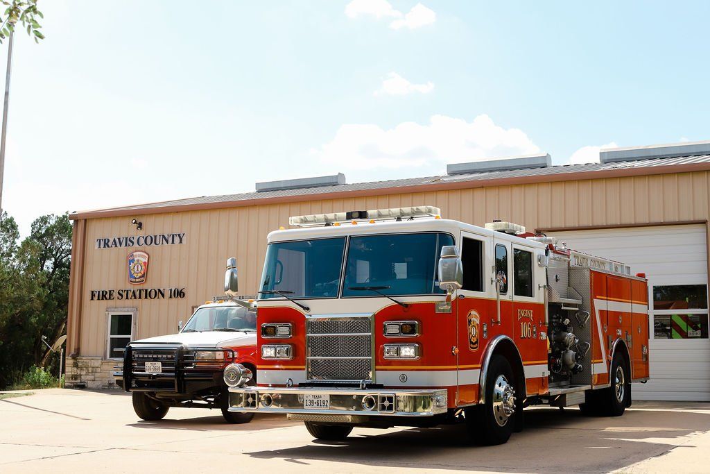 Two fire trucks are parked in front of a fire station