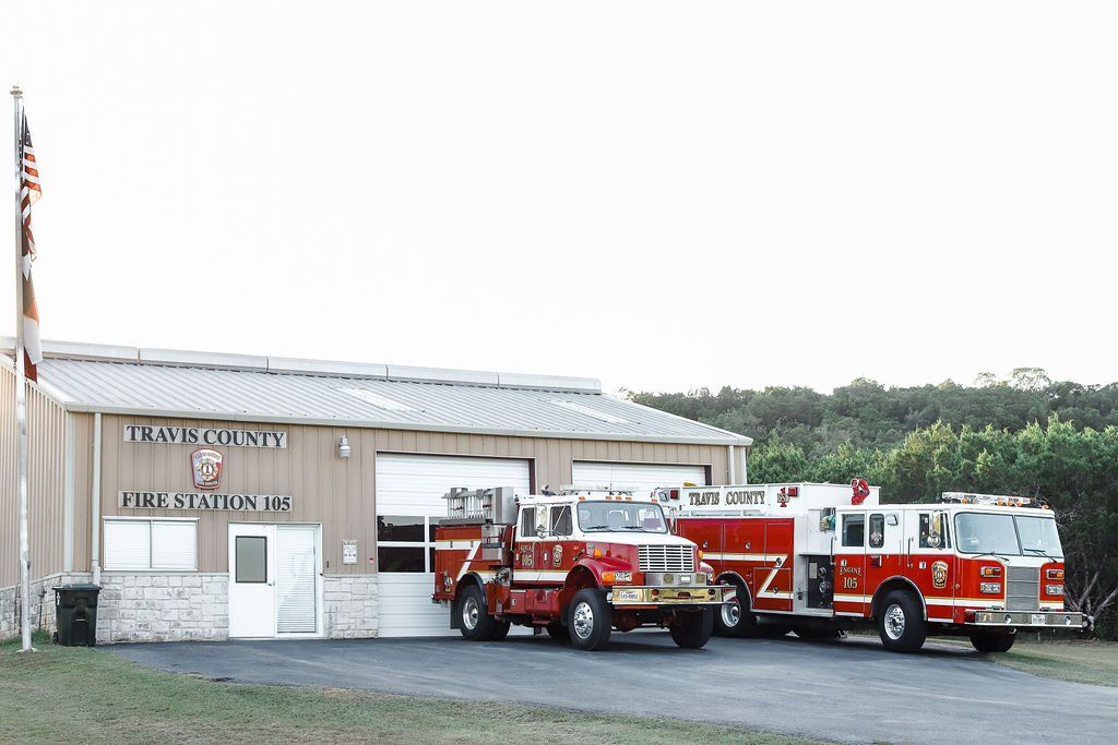 Two fire trucks are parked in front of a fire station