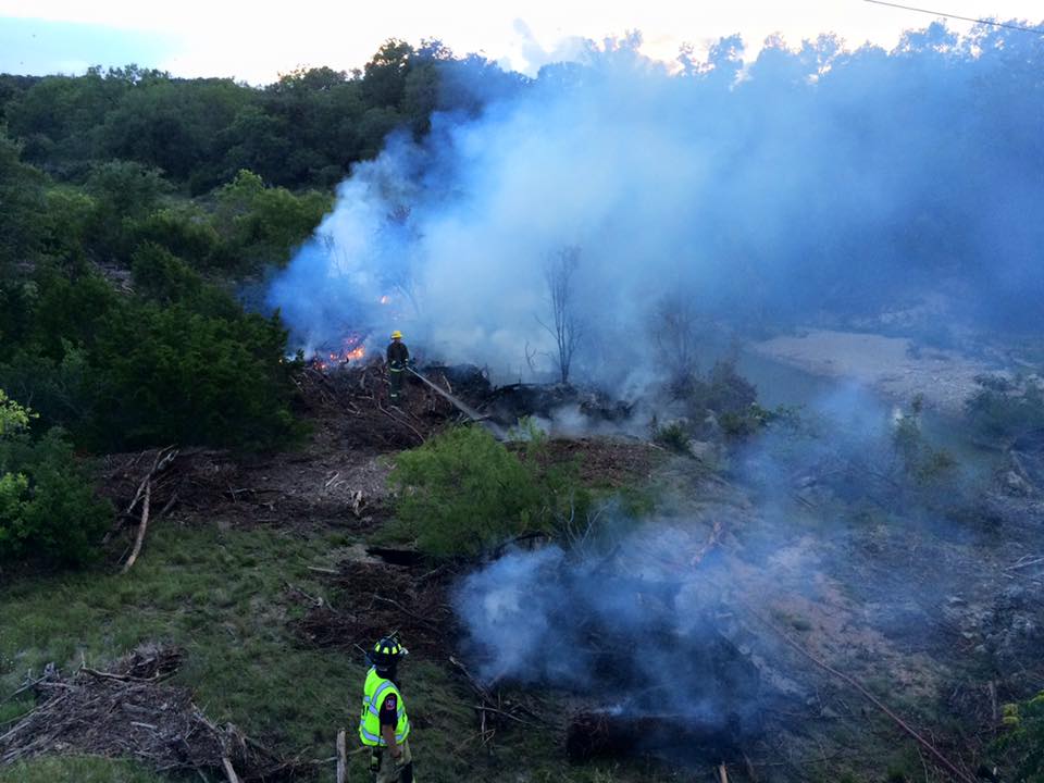 A firefighter is standing in front of a large forest fire.
