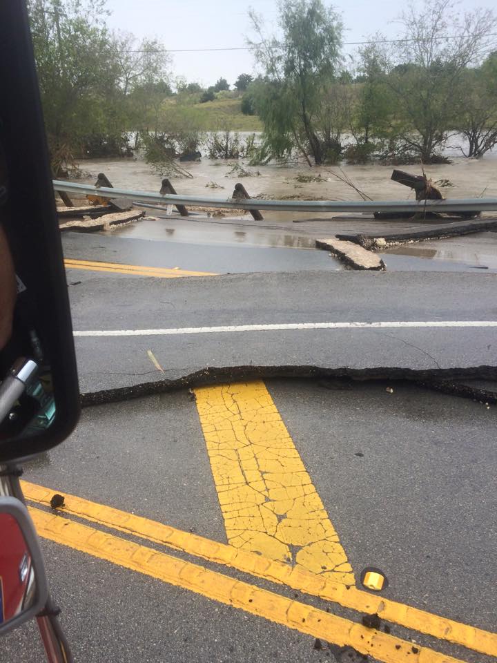 A car is driving down a road with a flooded area in the background