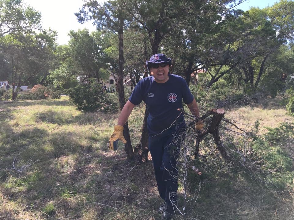 A man is walking through dragging a tree limb.