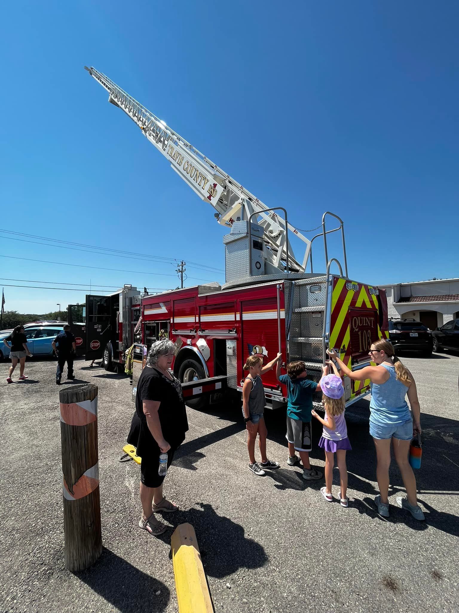 A group of people are standing around a fire truck in a parking lot.