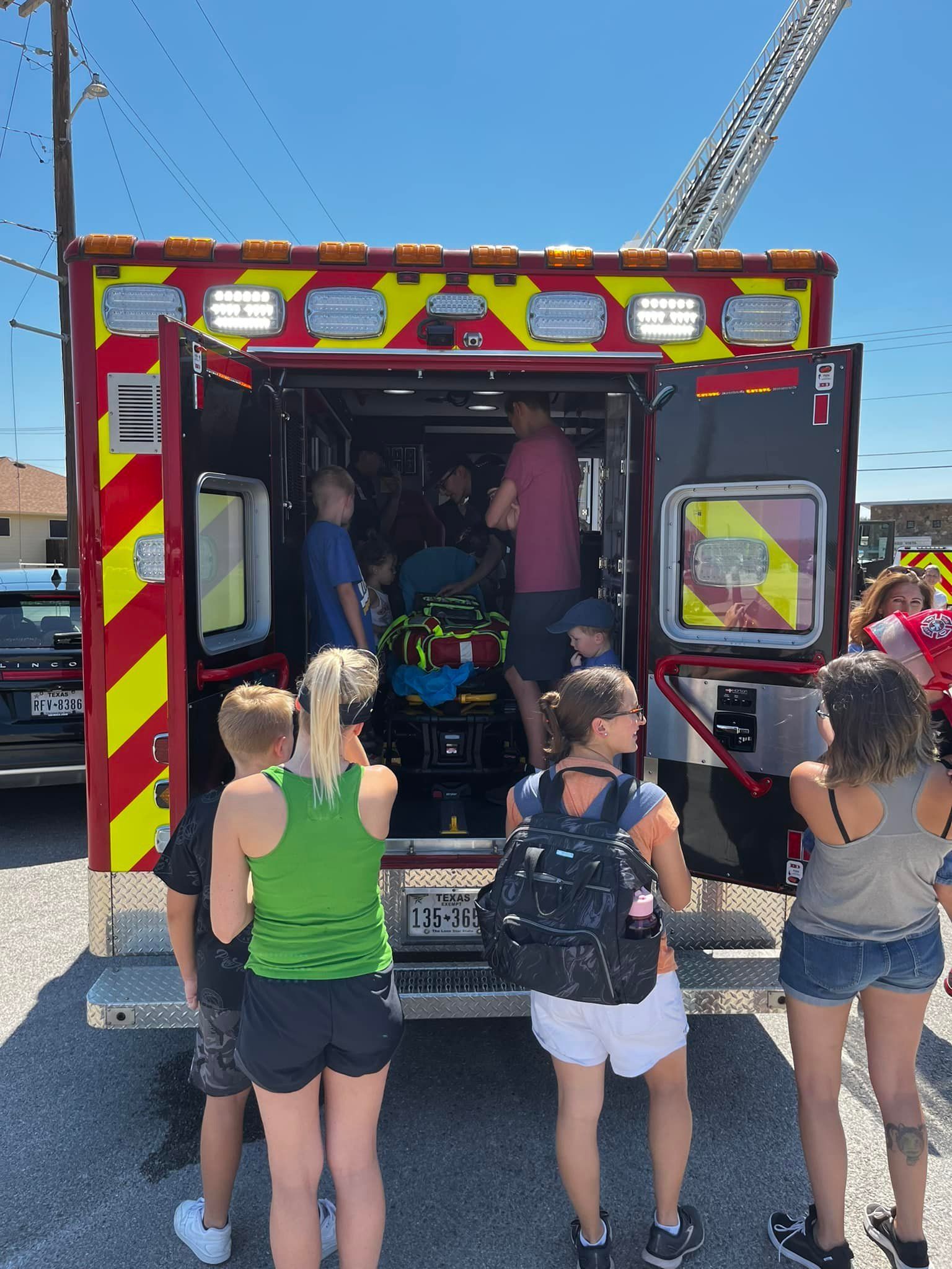 A group of children are standing in front of an ambulance.