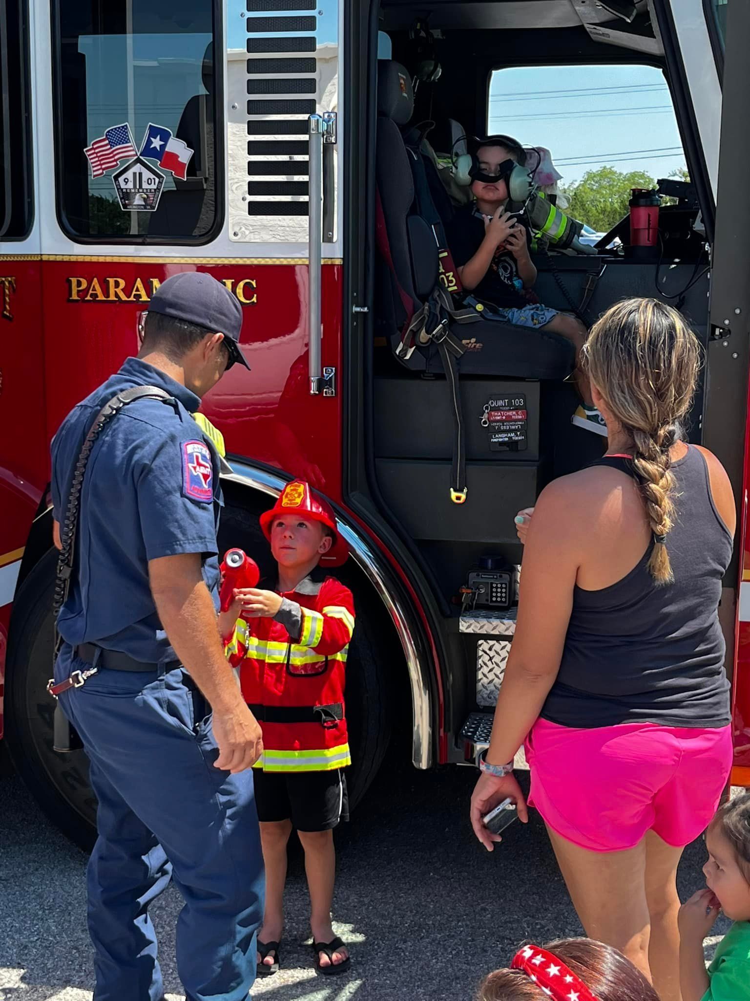 A group of people are standing in front of a fire truck.