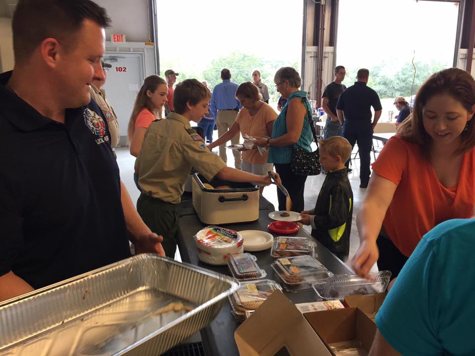A group of people are standing around a table serving food.