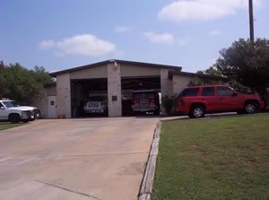 A red suv is parked in front of a fire station